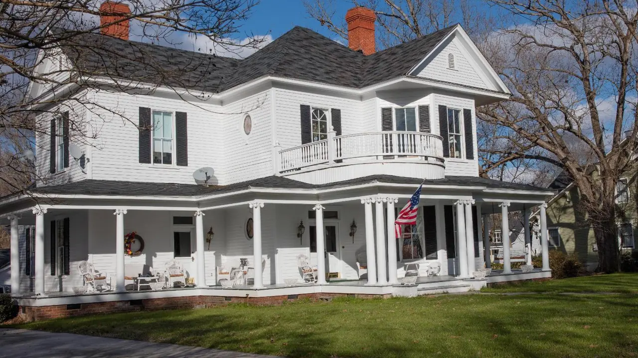 A white farmhouse with a wraparound porch