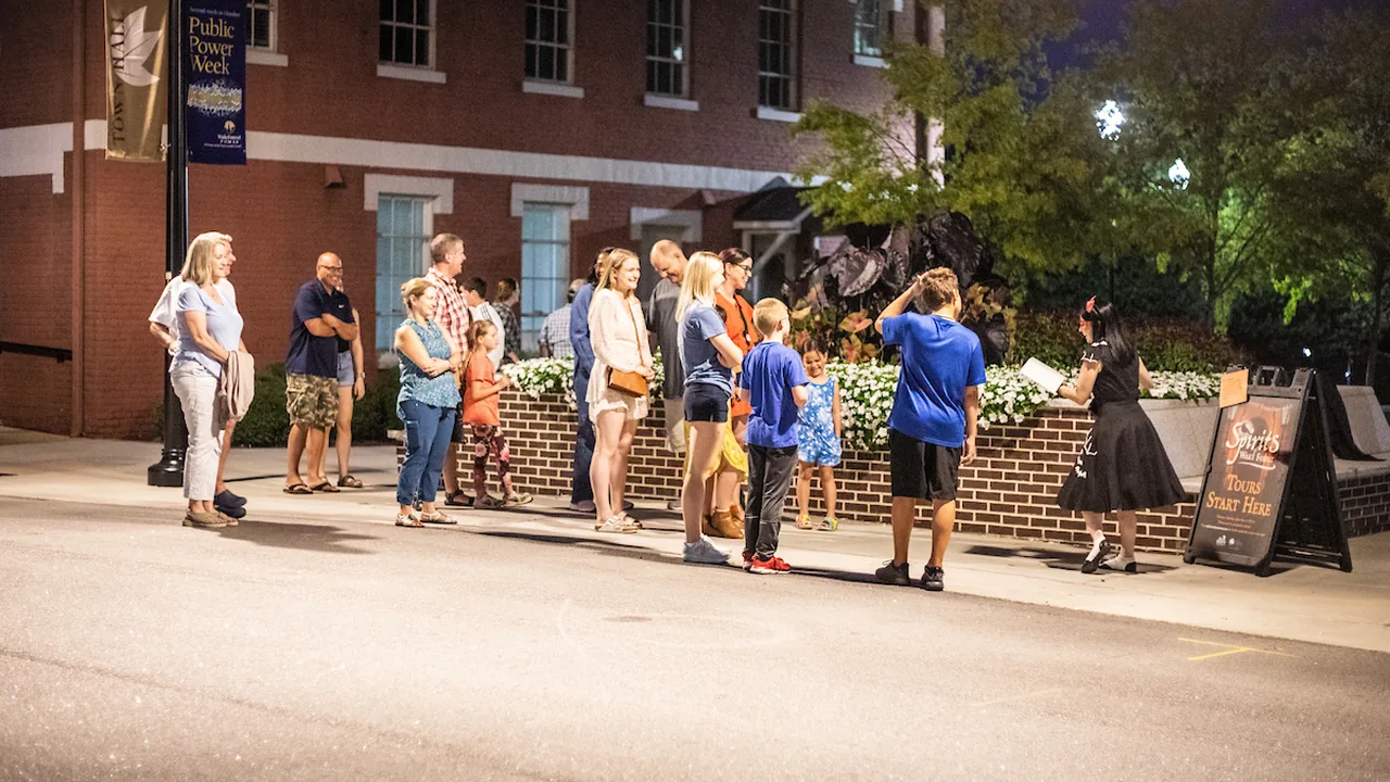 People gather on a downtown Wake Forest sidewalk at dusk