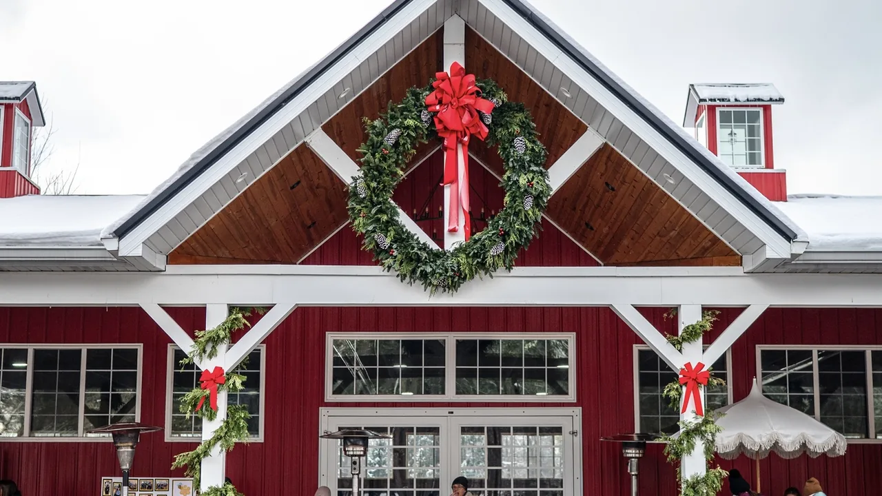 A red barn-style building with a big wreath and red bows over its front doors.