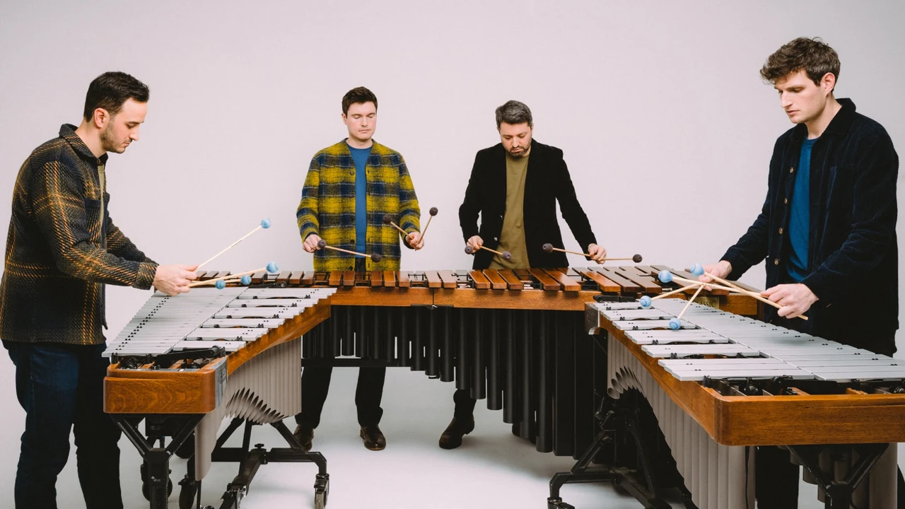 Four percussionists play marimbas in a white studio