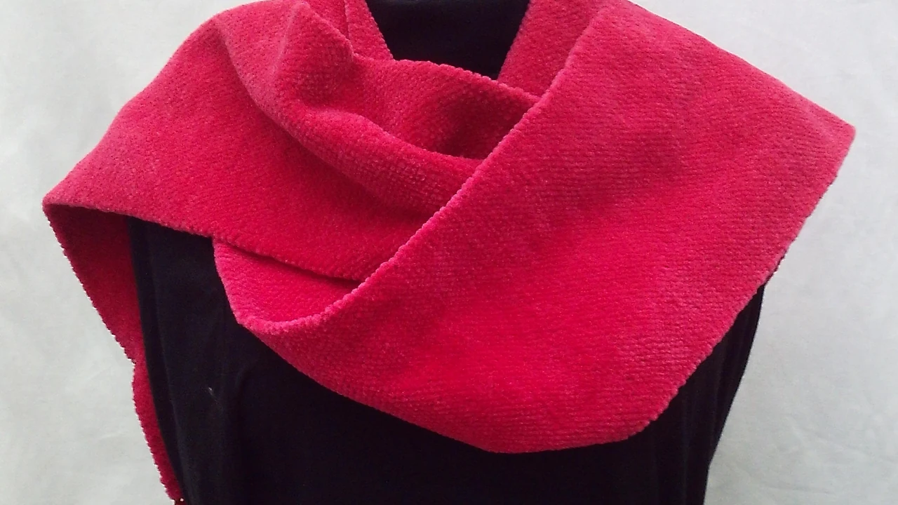 A handmade pink knit cowl on a display form