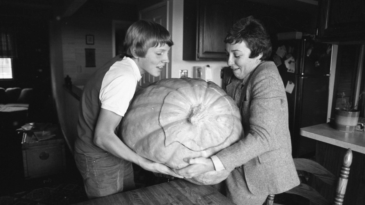 Two people hold a giant pumpkin in a vintage black-and-white photo