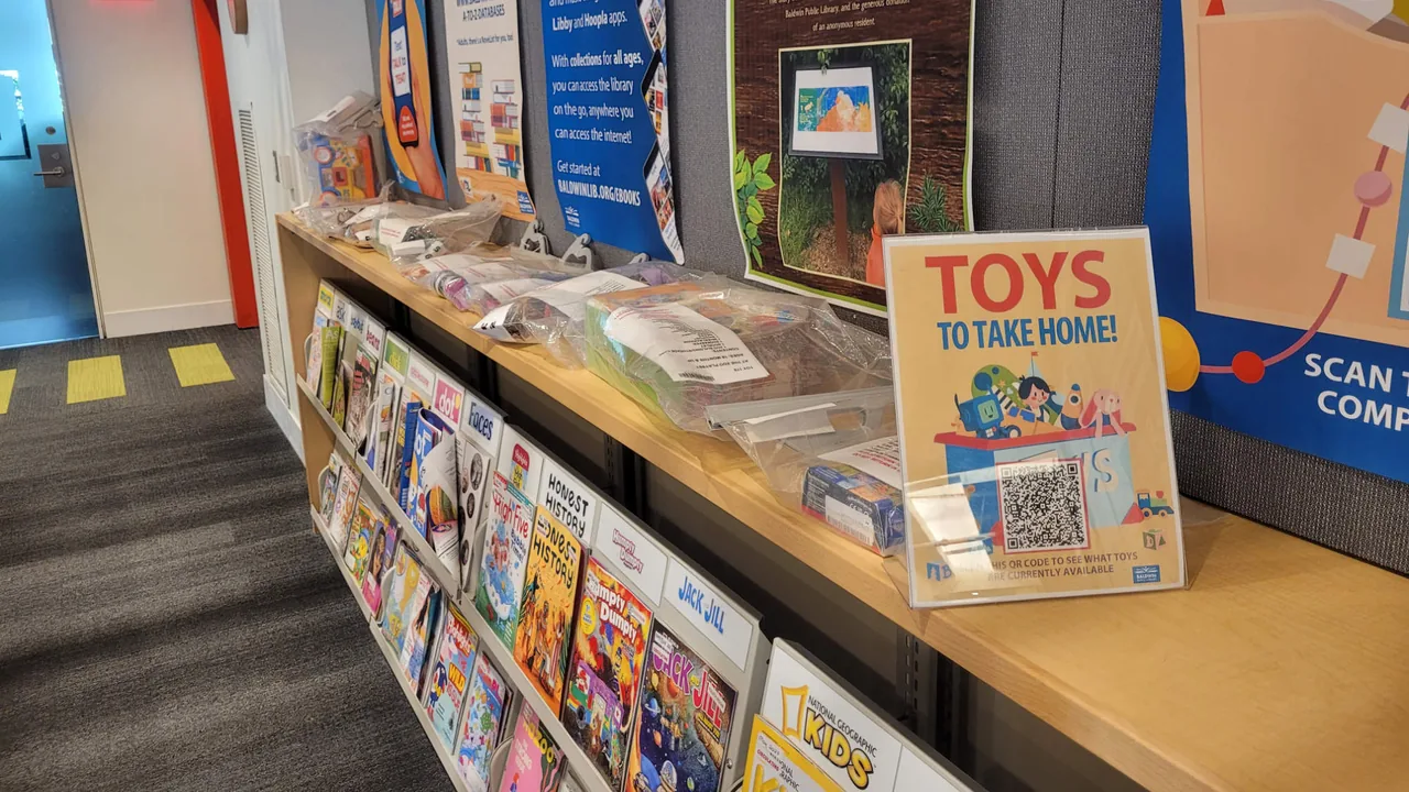 Library shelves with books and a Toys to Take Home display
