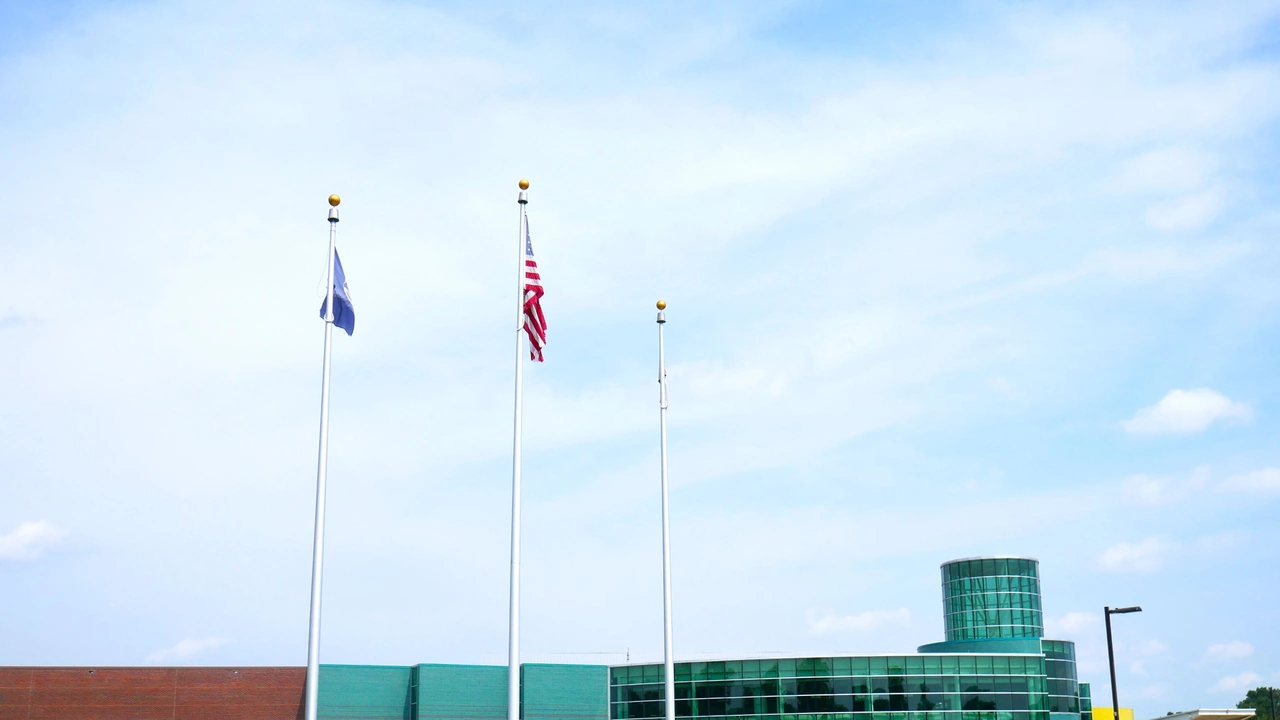 Flags fly on tall poles over a building under a blue sky