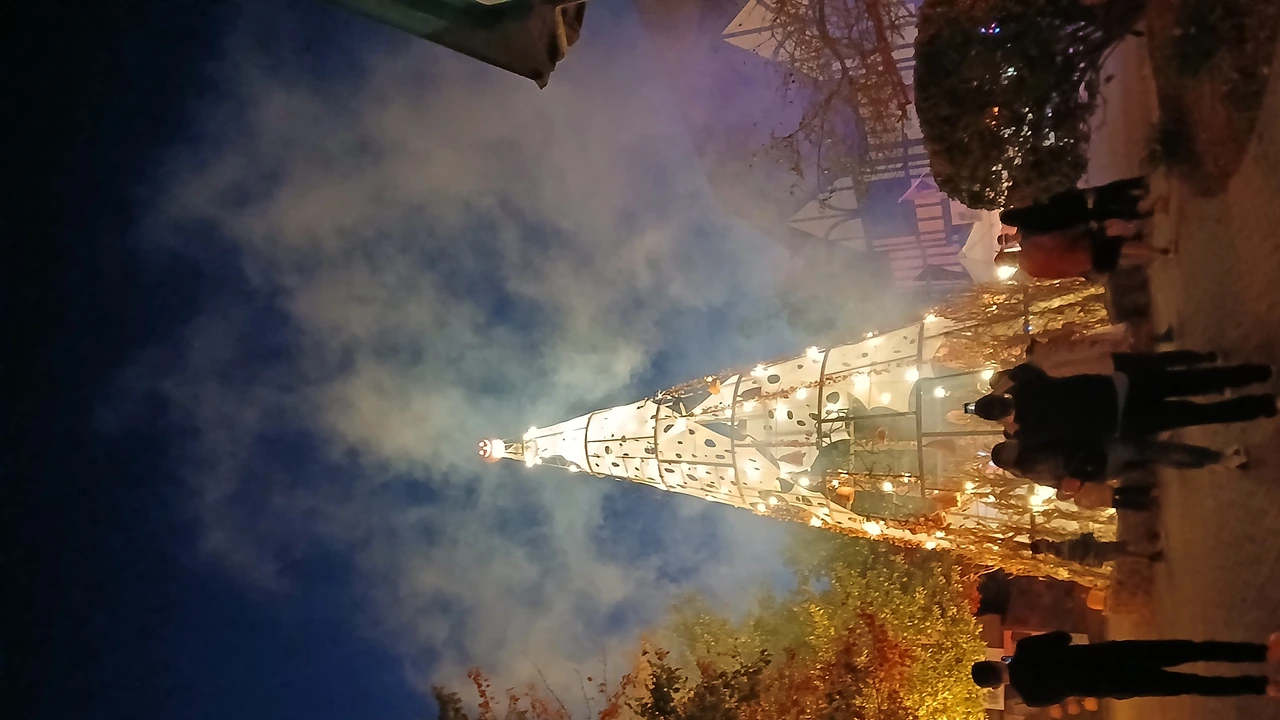 Visitors walk past a glowing lit tree in a smoky night scene