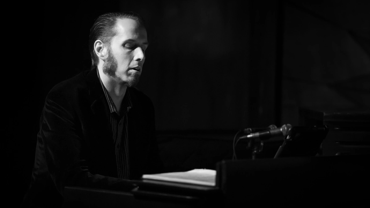 A pianist plays in near darkness