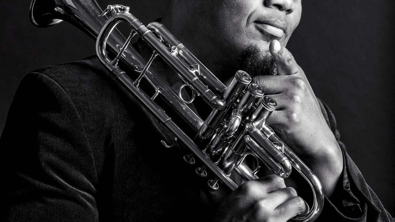 A musician holds a trumpet in a black-and-white portrait