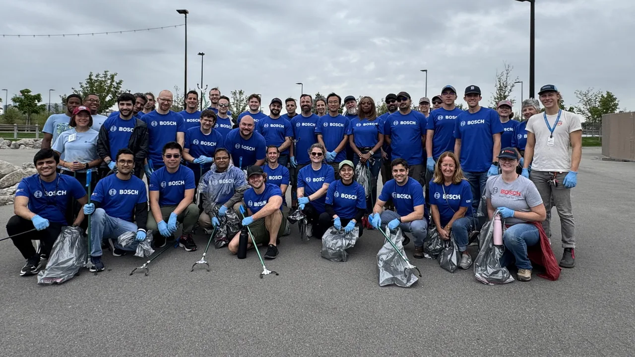 A large volunteer group in matching blue shirts poses in a parking lot