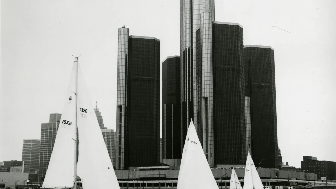 Sailboats pass the Detroit skyline in black and white