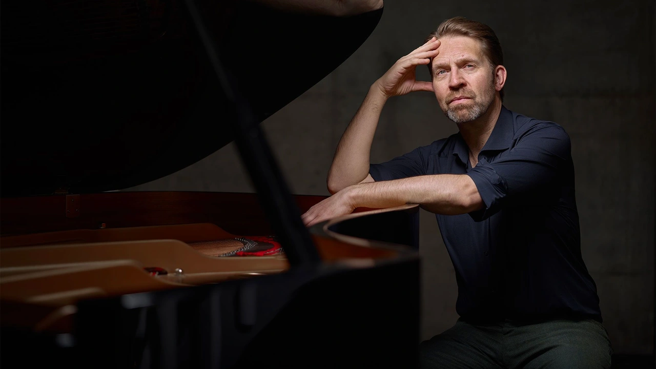 A pianist rests his head on his hand at a grand piano