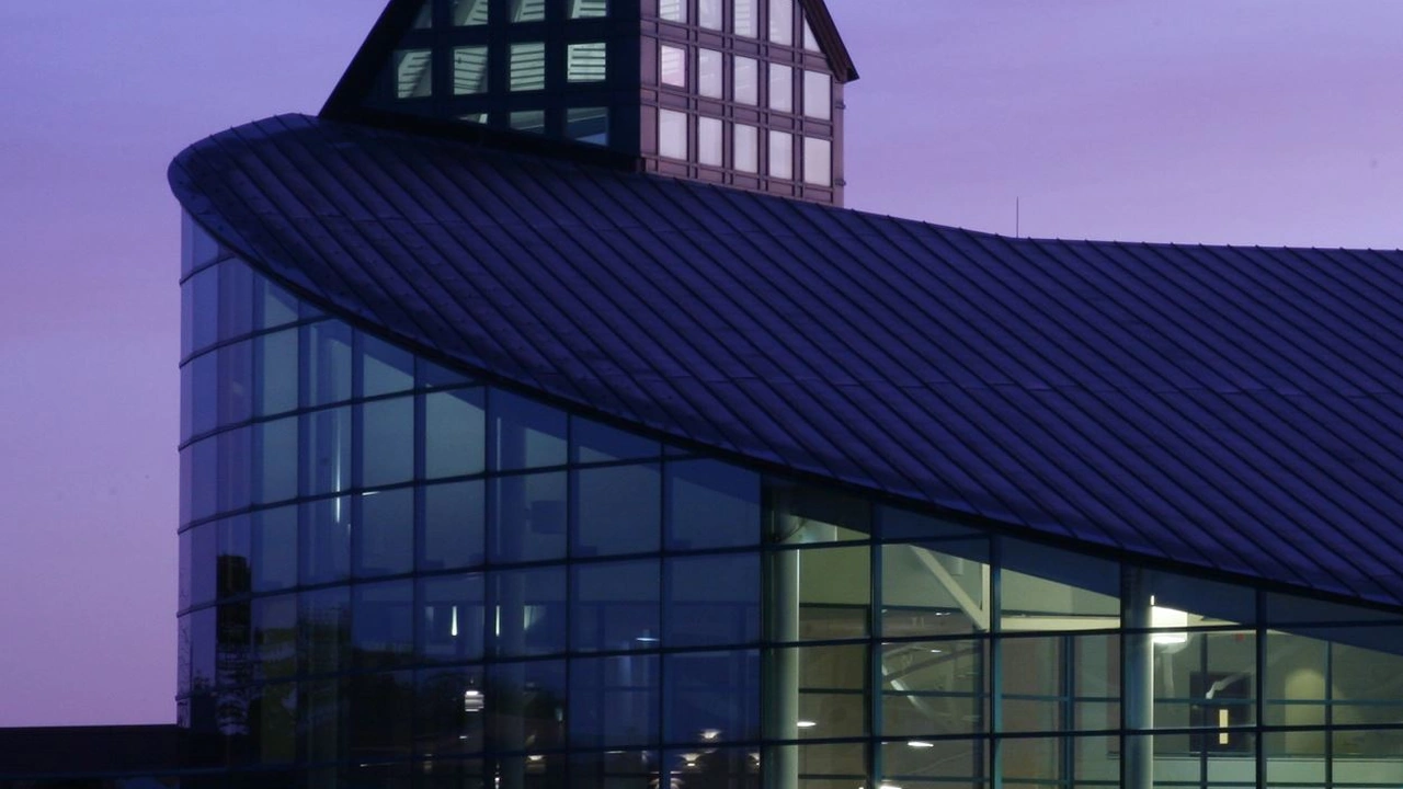 A curved glass building lit at dusk