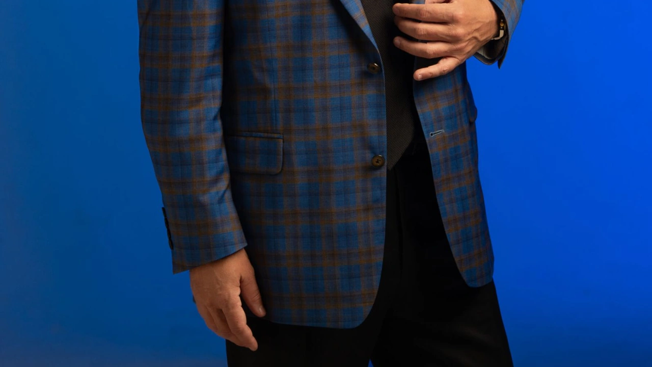 A performer in a plaid jacket against a bright blue background
