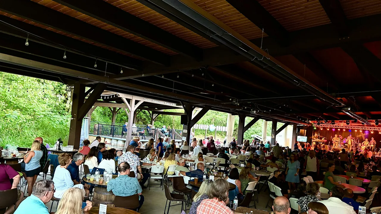 A crowd at tables under an open-air pavilion