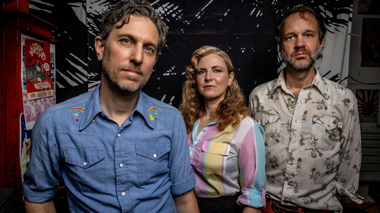 Three musicians pose before a dim backdrop