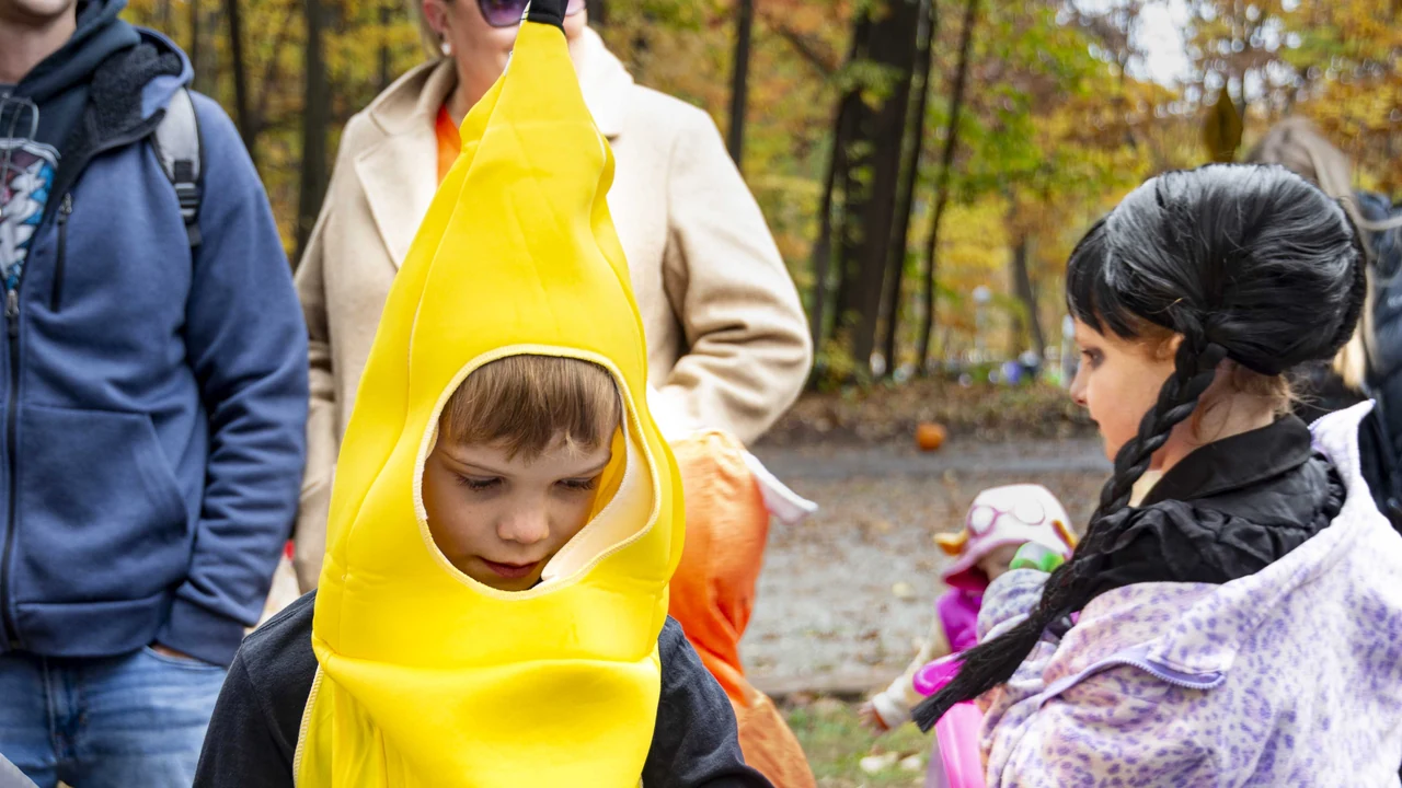 Children in Halloween costumes, one dressed as a banana, on a fall walk