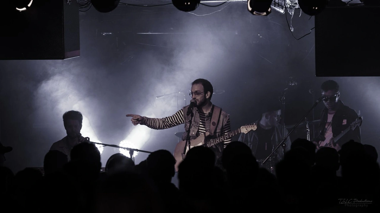 A guitarist performs in stage smoke above a silhouetted crowd
