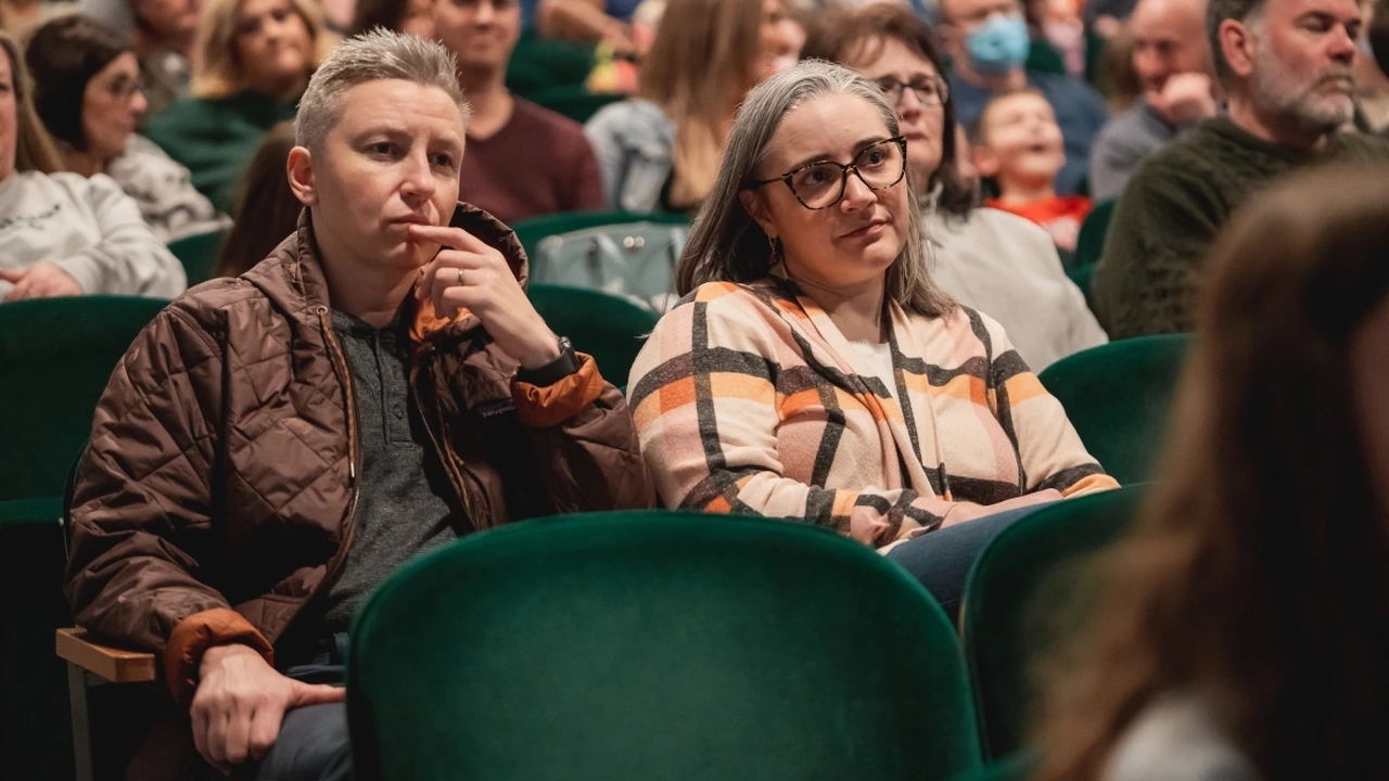 Audience members watch intently from theater seats