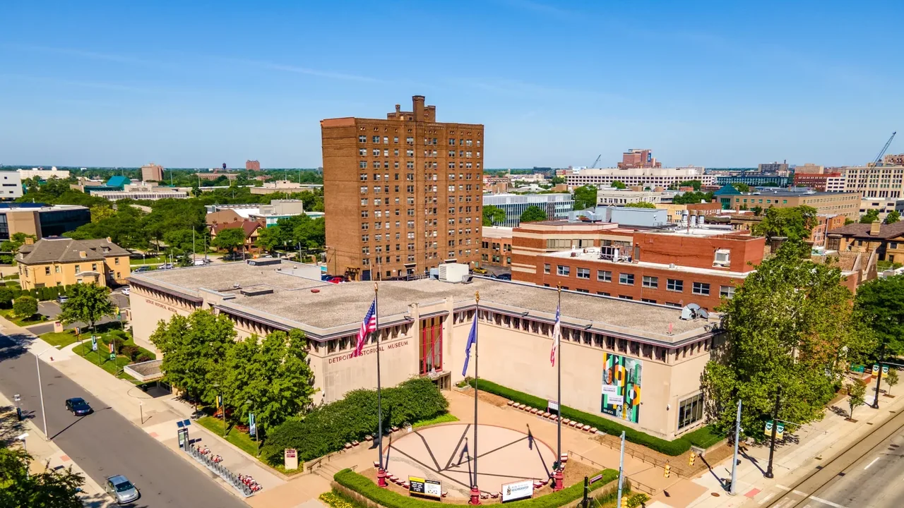 An aerial view of a small city center with a brick tower and tree-lined streets
