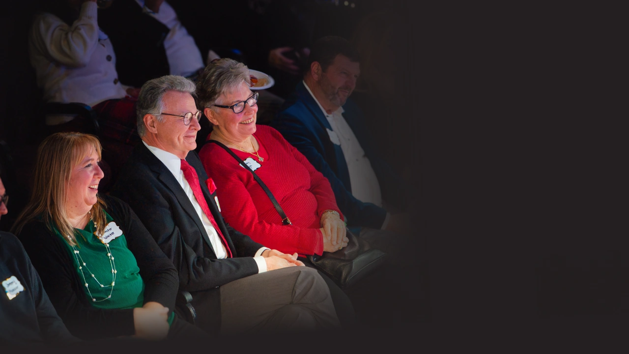 Audience members seated in a dim theater