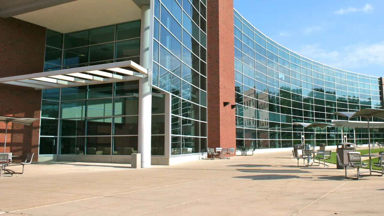 A curved glass-and-brick building entrance under blue sky