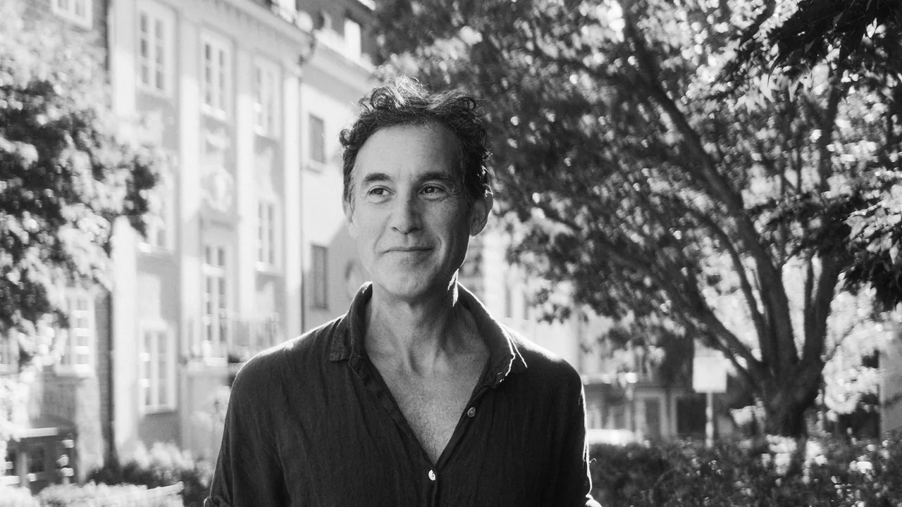 Black-and-white portrait of a man on a tree-lined street