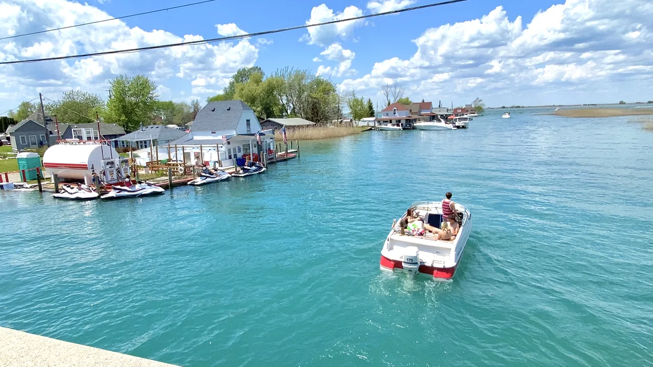 A small boat cruises a blue channel past waterfront cottages
