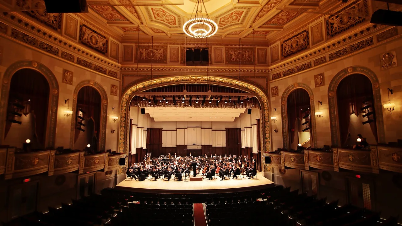 An orchestra on stage in an ornate gilded concert hall