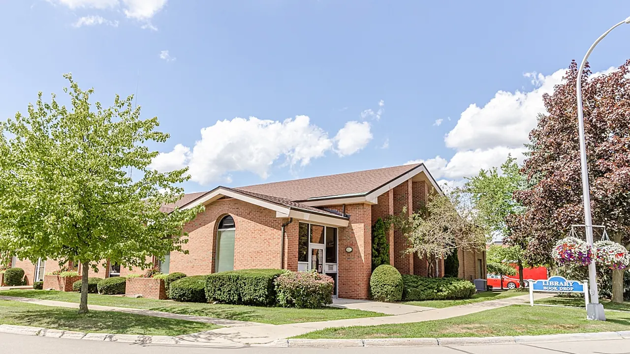 A brick ranch house with trees under a blue sky