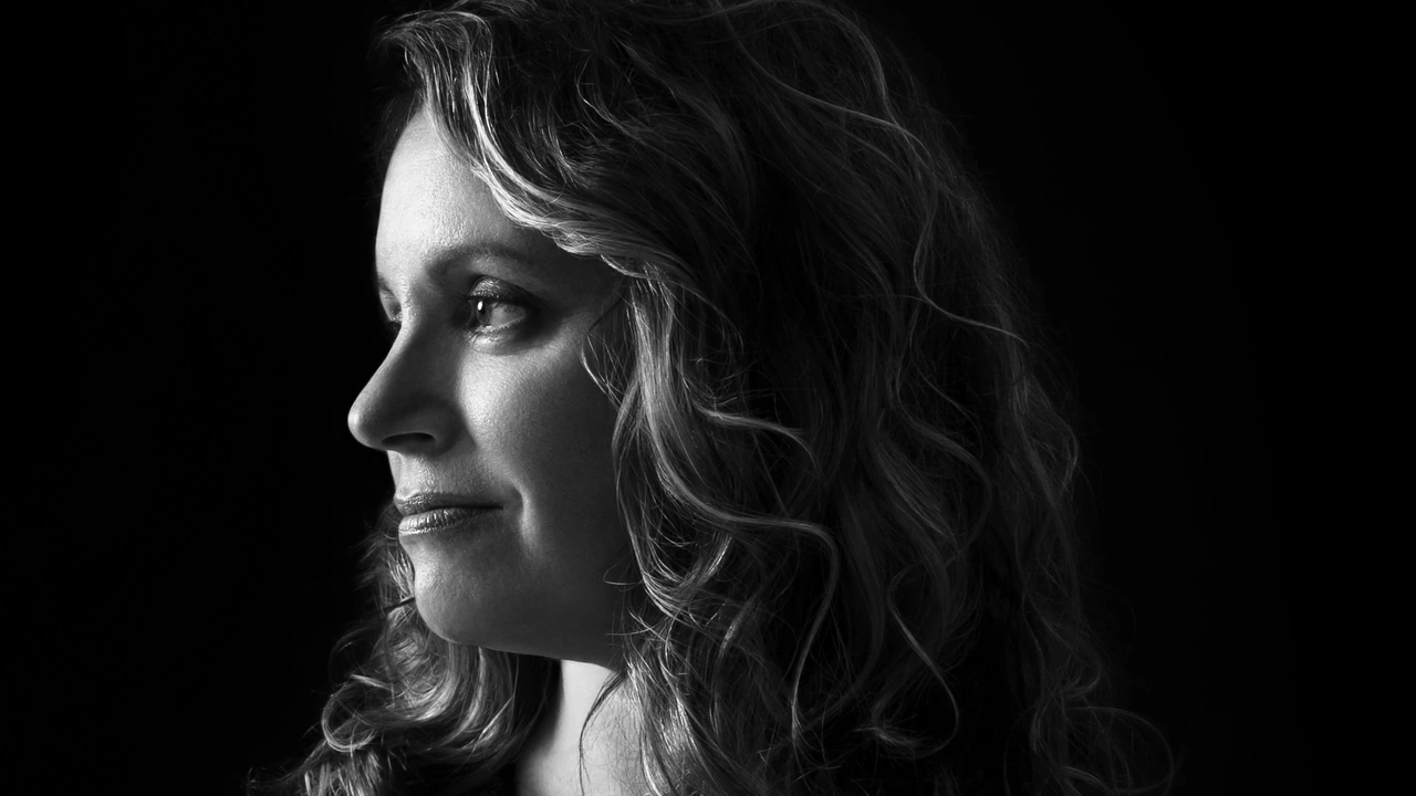 Profile portrait of a woman with curly hair against black