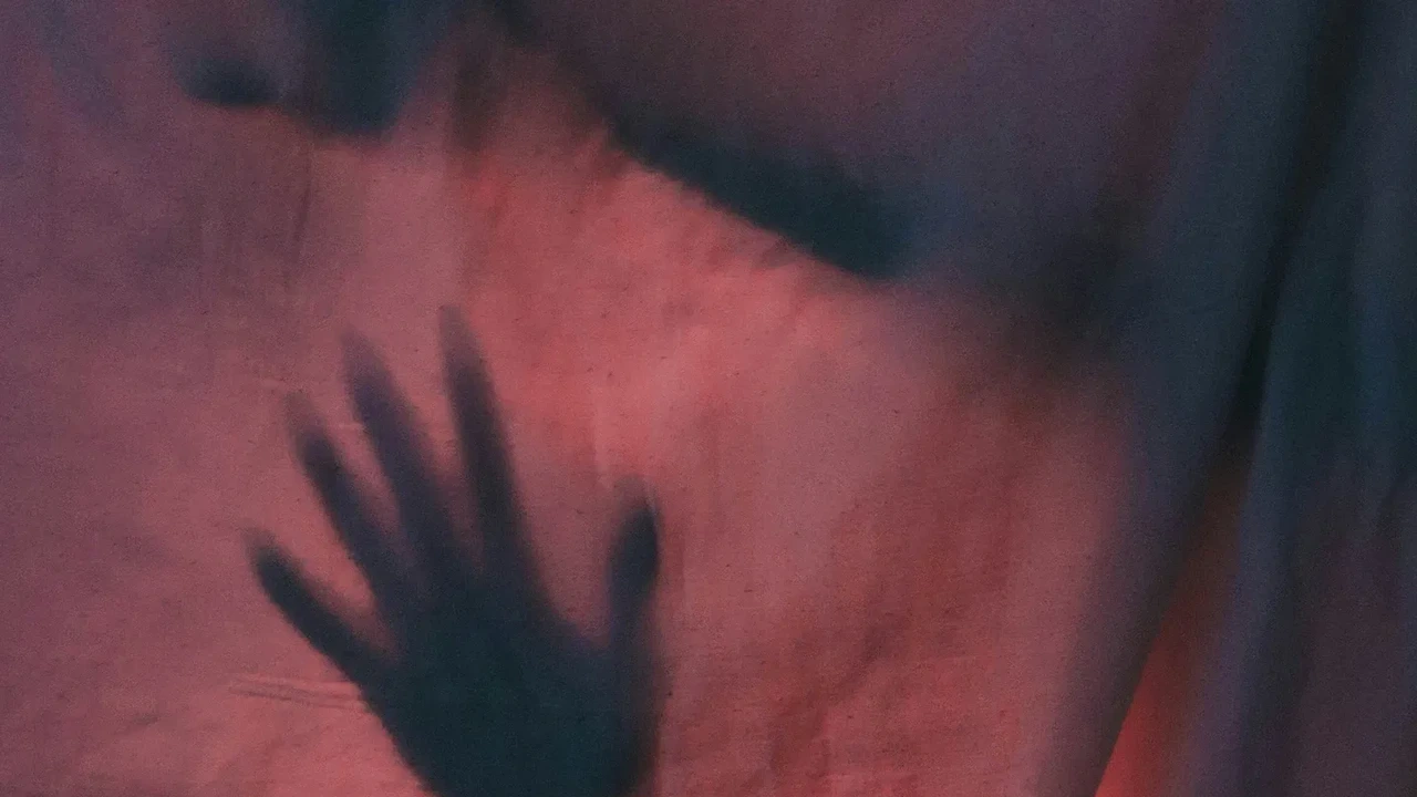 The shadow of a hand against a red-lit wall