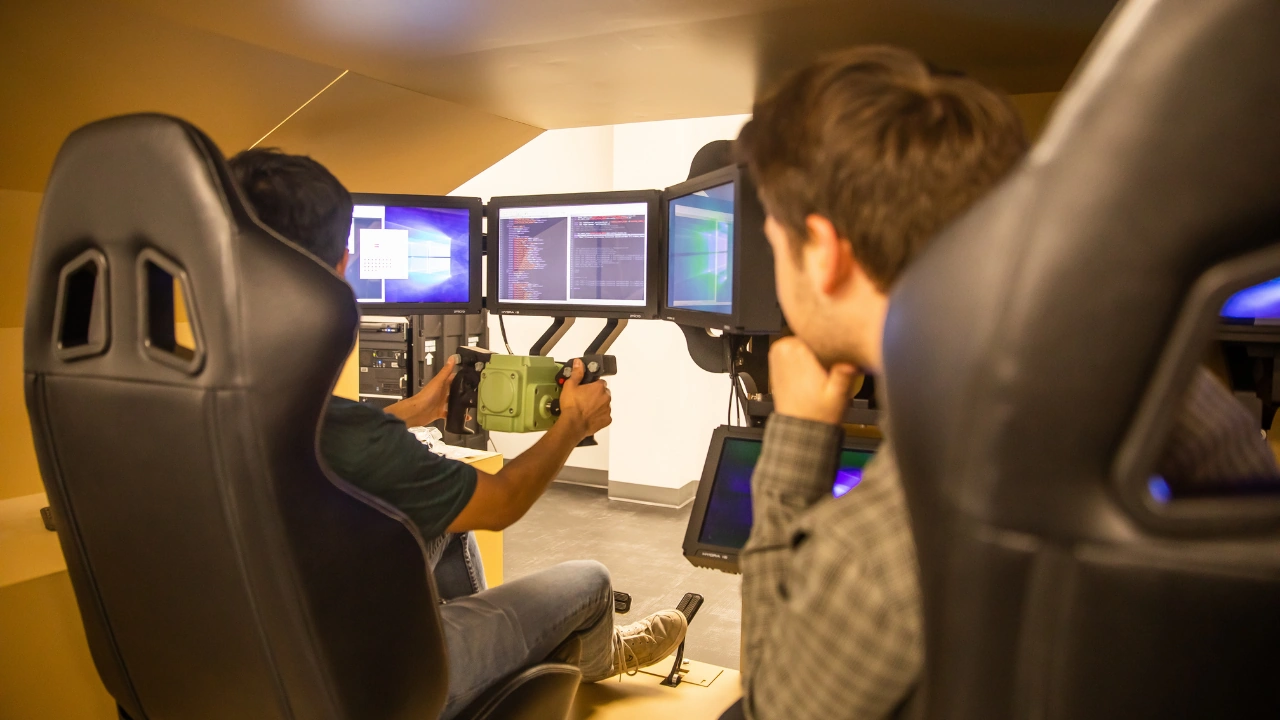 Players sit at racing-style gaming chairs facing glowing screens