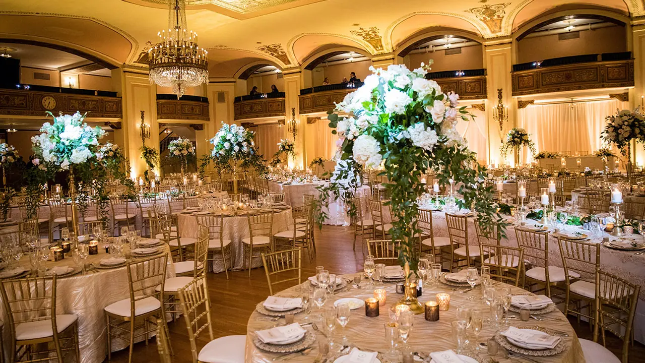 An elegant banquet hall set with round tables and tall floral centerpieces