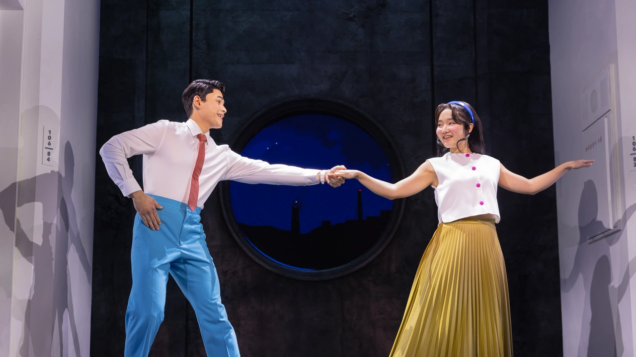 Two performers in period costume dance on a stage