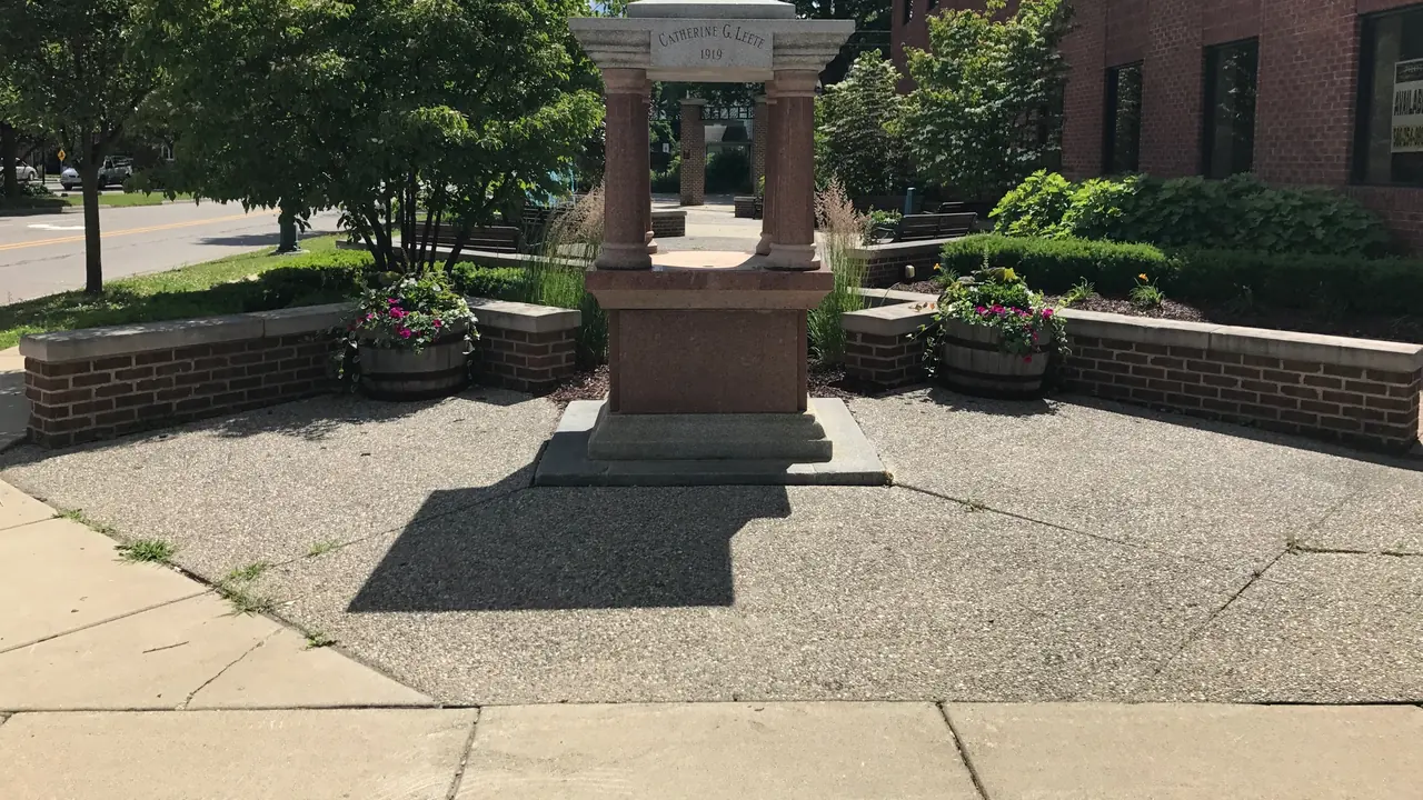 A brick courtyard with a fountain and planters
