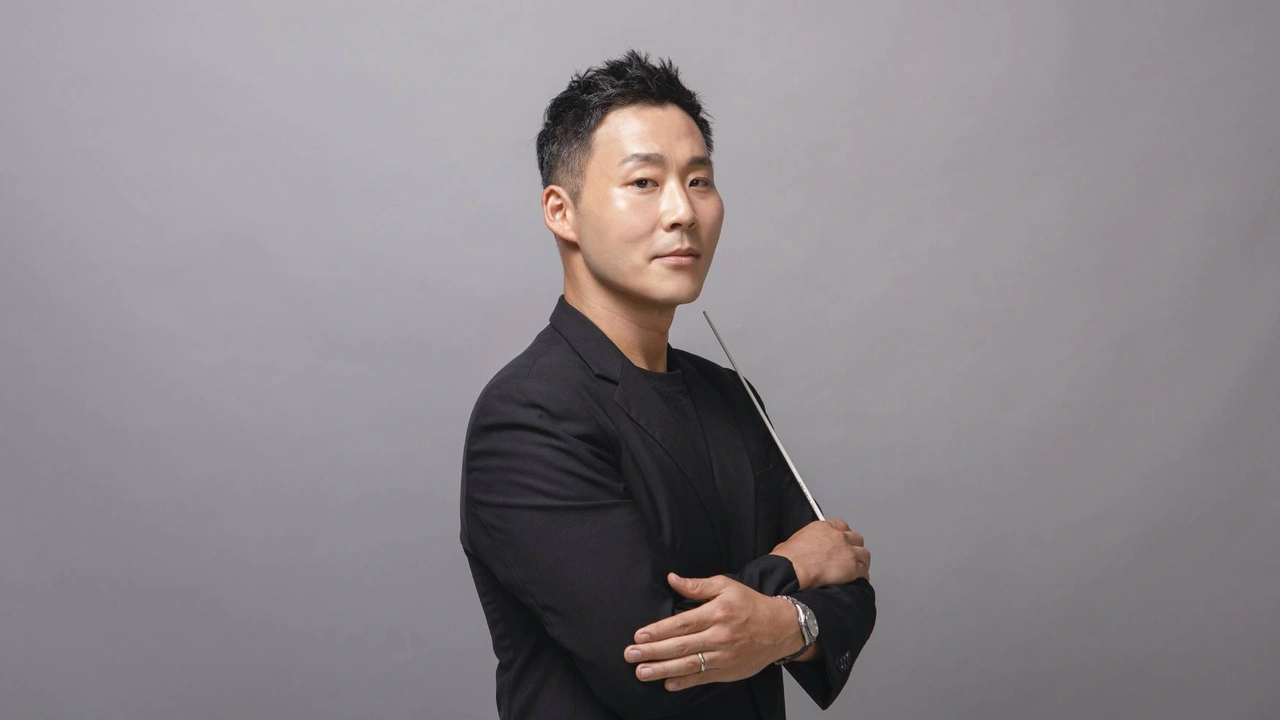 A man in a black suit poses with his arms crossed