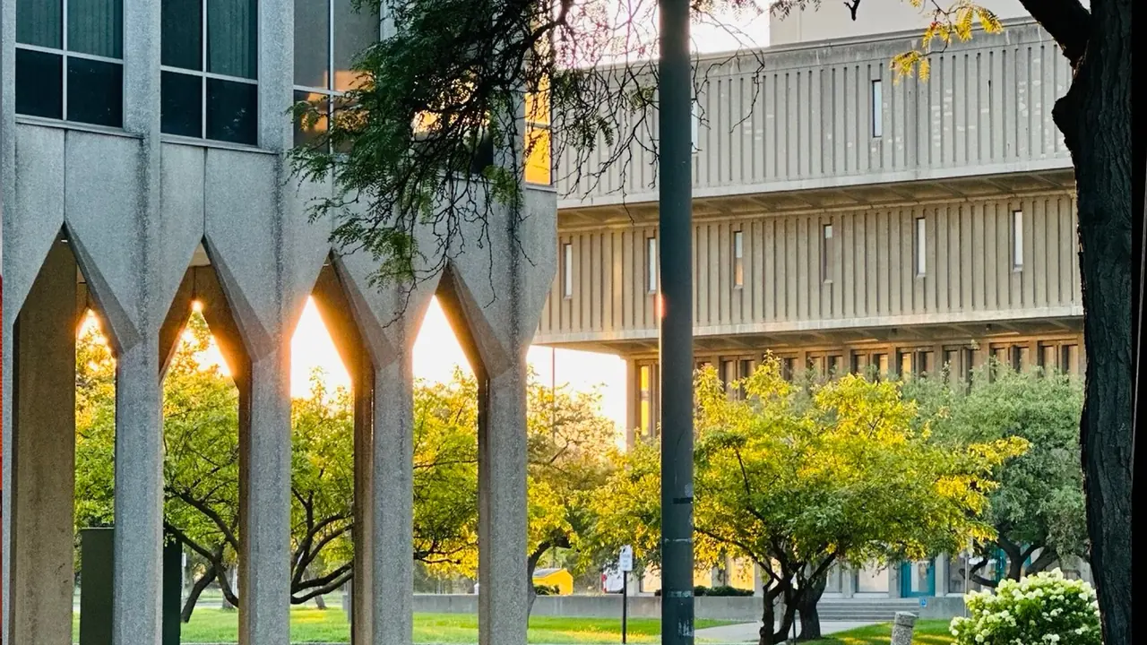 Gothic-arched campus building behind autumn trees