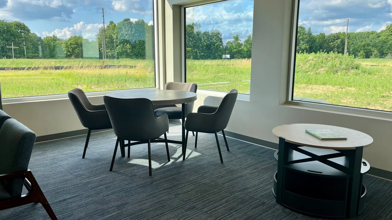 A bright room with tables and chairs overlooking green fields