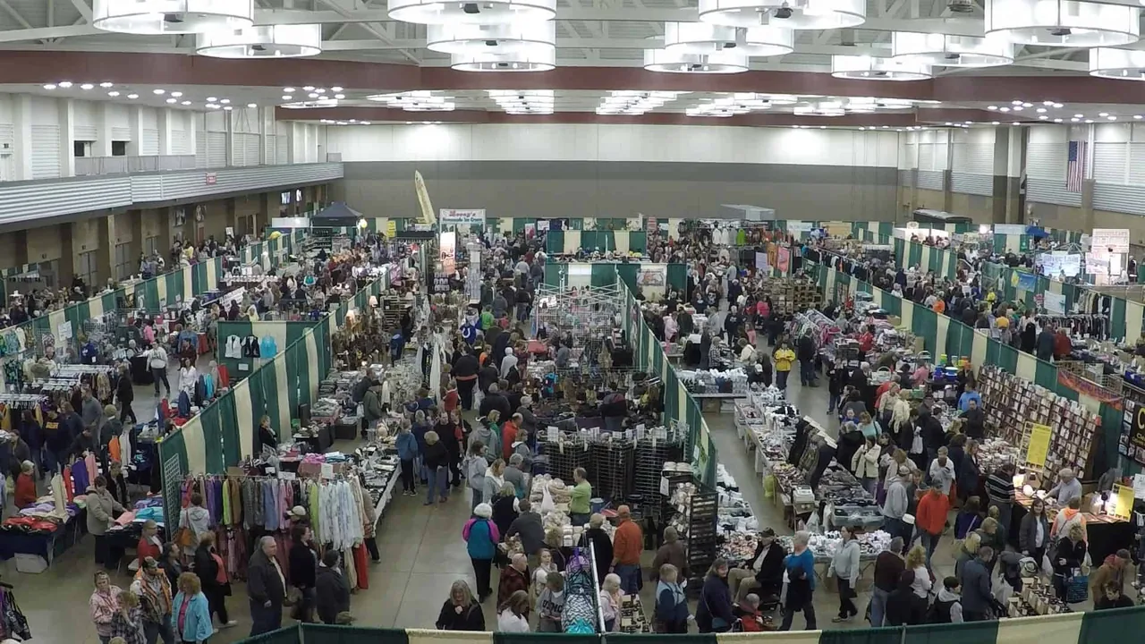 A large exhibition hall packed with vendor booths and shoppers seen from above.