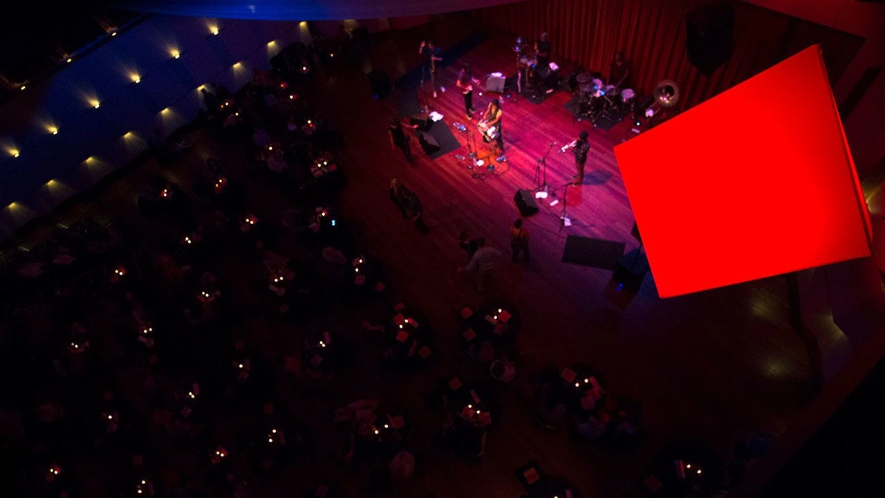An overhead view of an orchestra hall with a red-lit stage