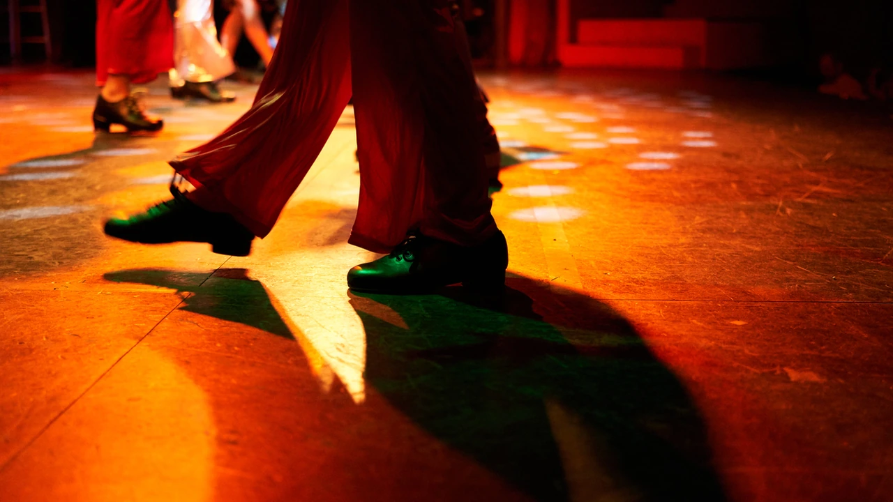 Dancers' legs and shoes on a stage lit in red and orange