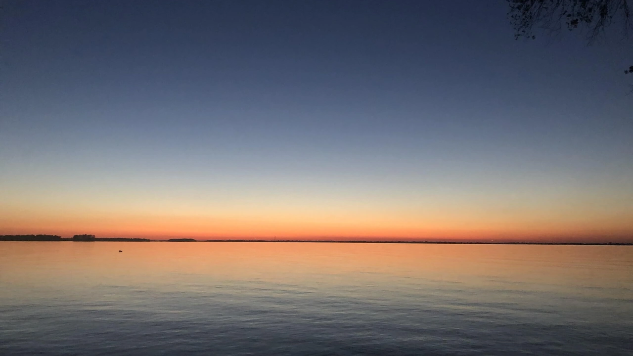 A calm lake at sunset under an orange sky