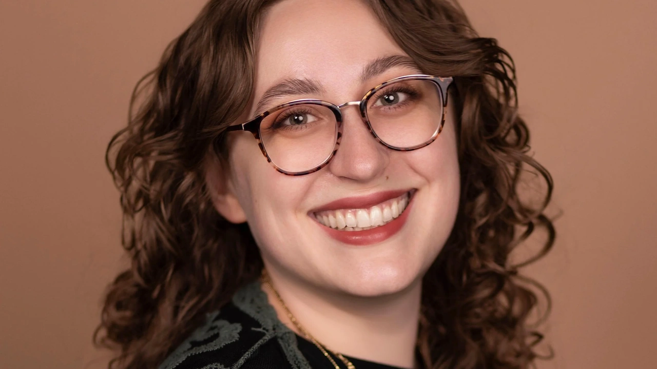 A smiling woman with curly hair and glasses