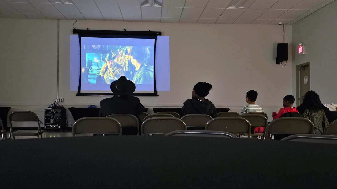 A small audience watches a film on a projection screen