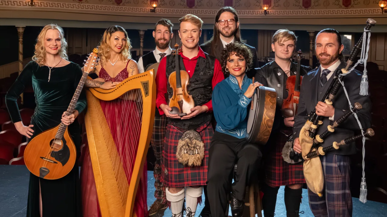 A Celtic band with harp, pipes and guitars poses on a stage