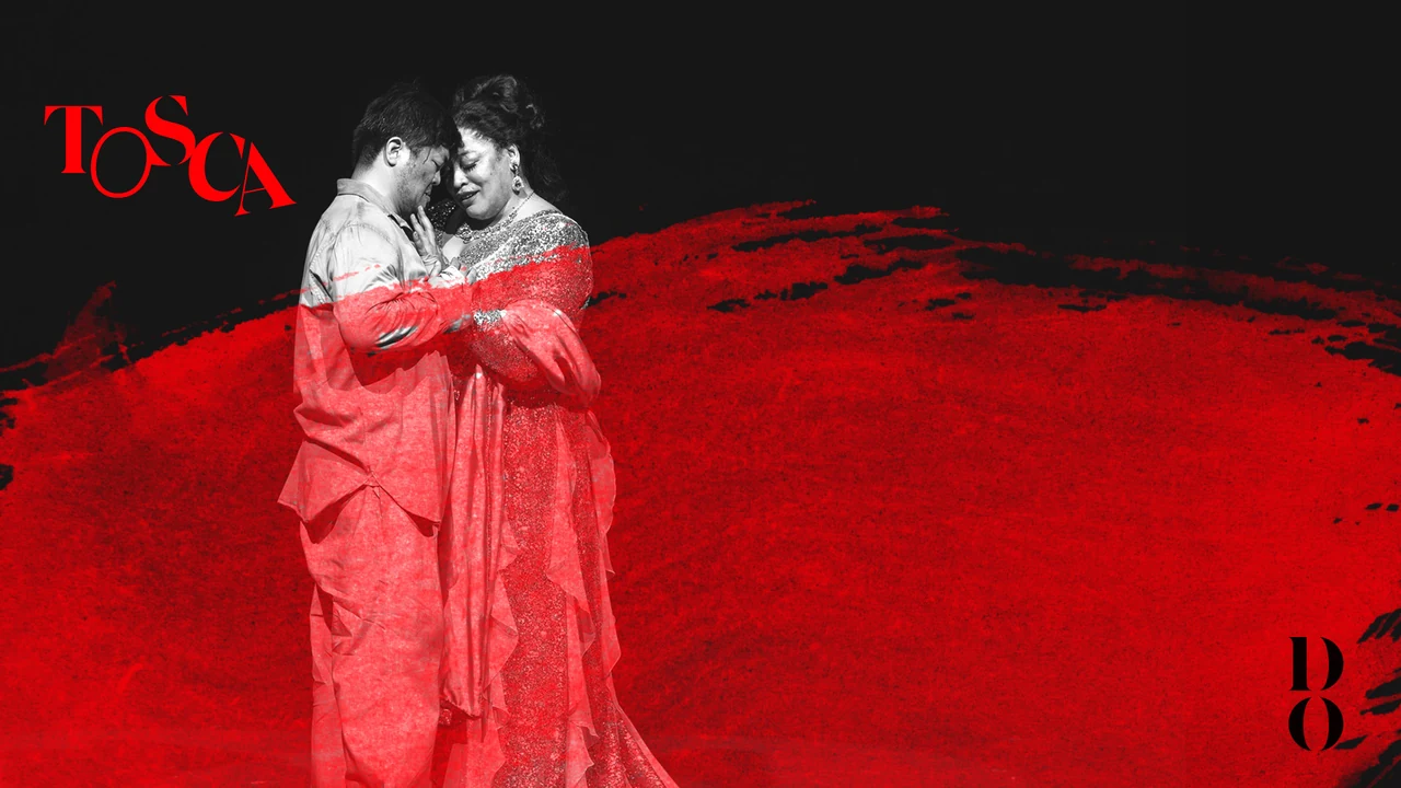 Two Tosca singers embrace in red costume against a dark backdrop
