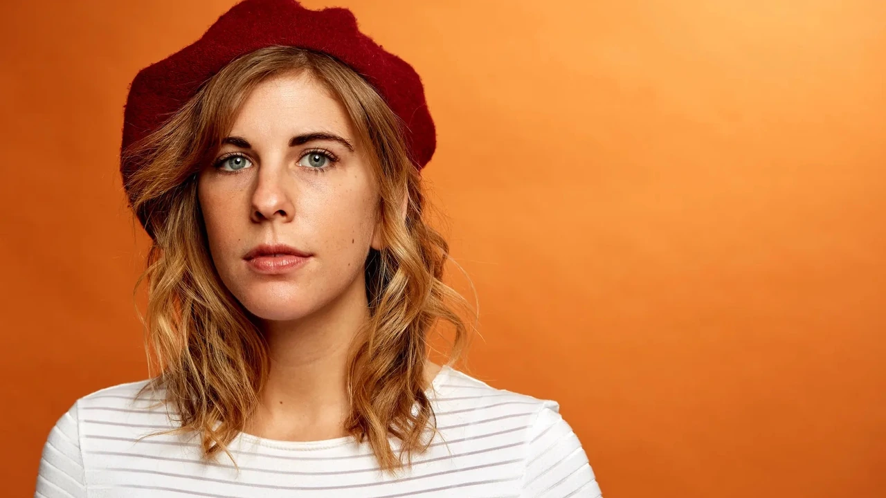 Portrait of a woman with wavy hair in a red beret against an orange wall